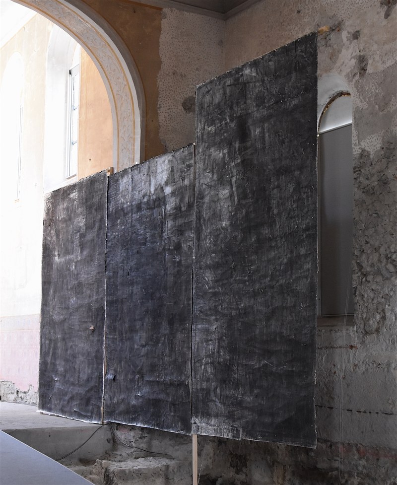 Vor der rechten Wand des Kirchenschiffes hängen drei riesige Kohlebilder aus einer früheren Schaffensperiode von Christoph Luger