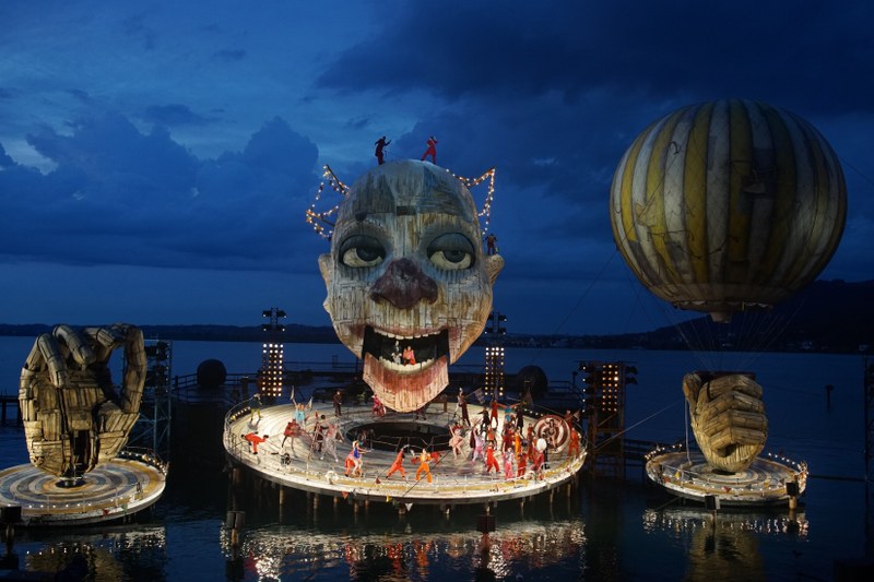 Der überdimensionale Kopf, mit vielen technischen Spielarten ausgestattet, ist ein Spiegelbild der Befindlichkeiten von Rigoletto. Der geöffnete Mund dient auch dem Herzog als Liebeslaube für seine Amouren.