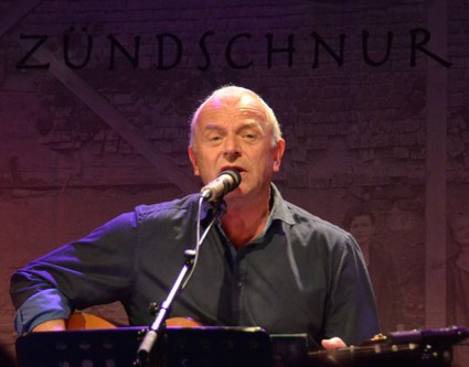 Ulli Troy - alias Zündschnur - suchte die Lieder, schrieb die Texte und prägt mit seinem Spiel mit den Worten und dem Dialekt die Musik von "Zündschnur und Bänd".