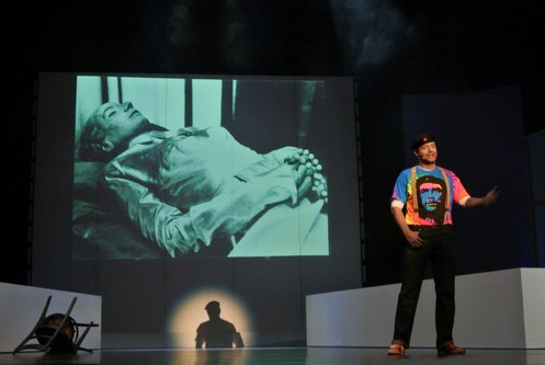 Martin Werth als Che (Guevara) ist Revoluzzer, „Stimme des Volkes“ und Erzähler der Handlung in einem. Im Hintergrund das Originalfoto der „echten“ Evita auf dem Totenbett.