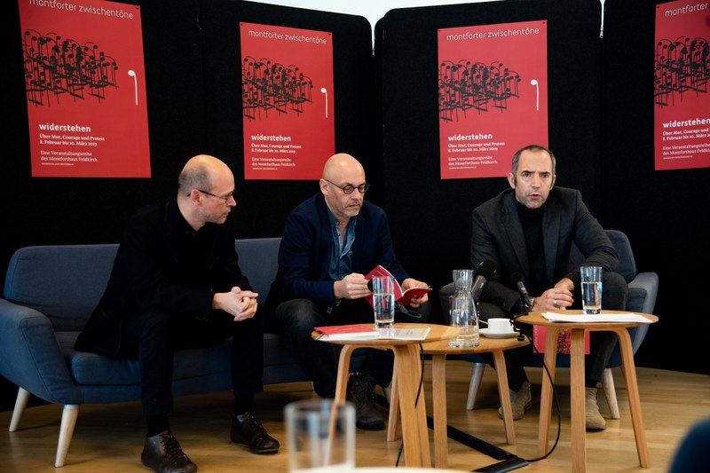 Hans-Joachim Gögl, Folkert Uhde und Edgar Eller präsentierten das aktuelle Programm der Montforter Zwischentöne vor dem aussagekräftigen Plakat zum Thema "widerstehen" von Reinold Luger. (Foto: Victor Marin)